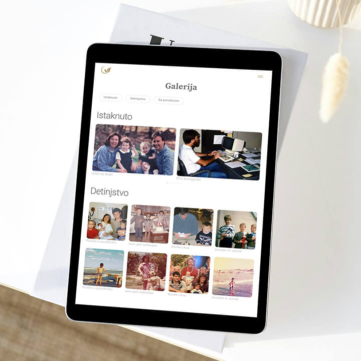 Na slici je prikazan tablet koji stoji na stolu i na čijem ekranu je prikazana galerija digitalnog spomenika.